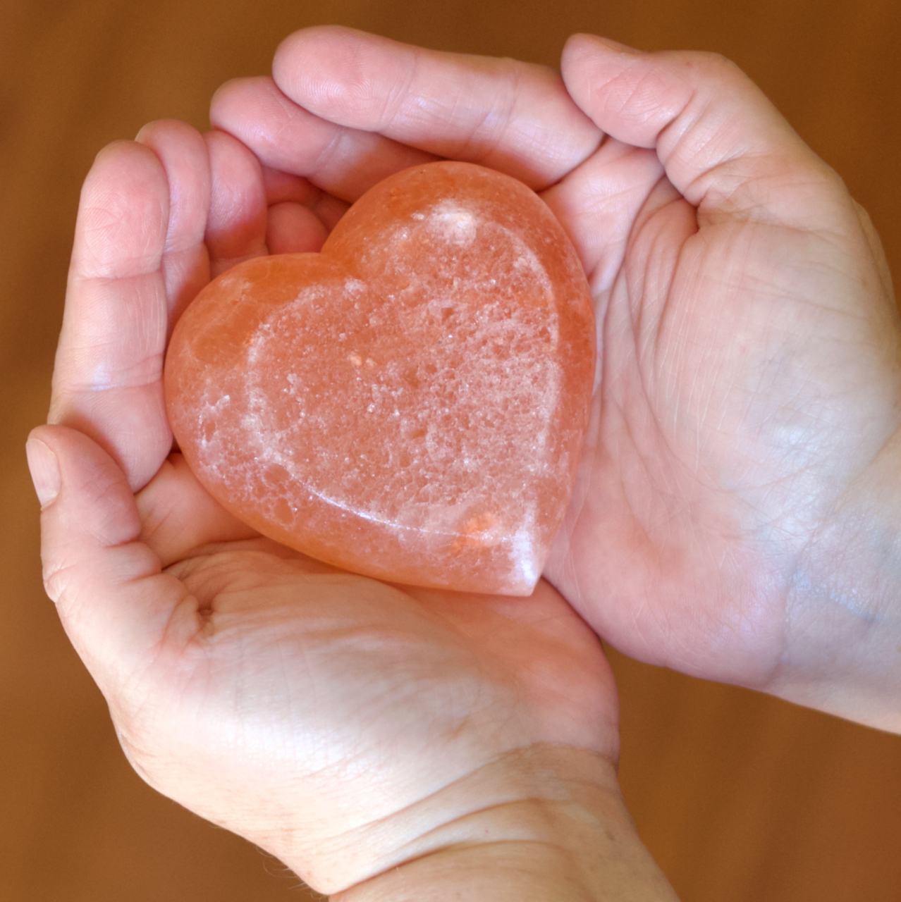 Hands cradling a rose quartz heart